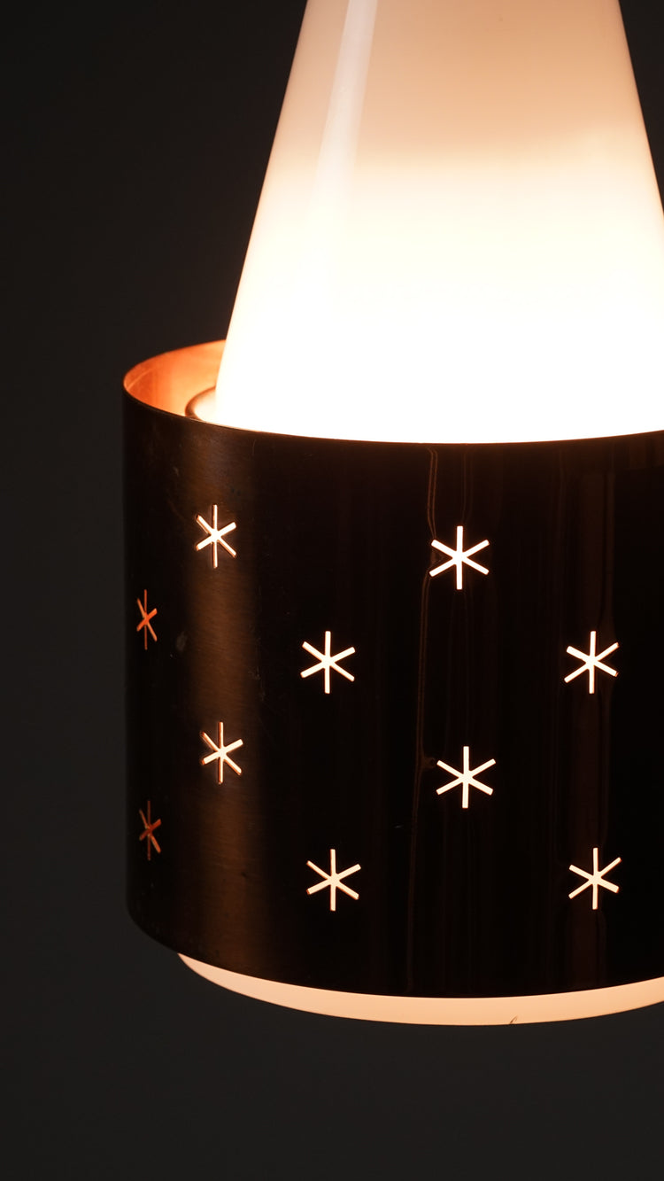 Opal glass lamp with a copper shade that has star-shaped holes