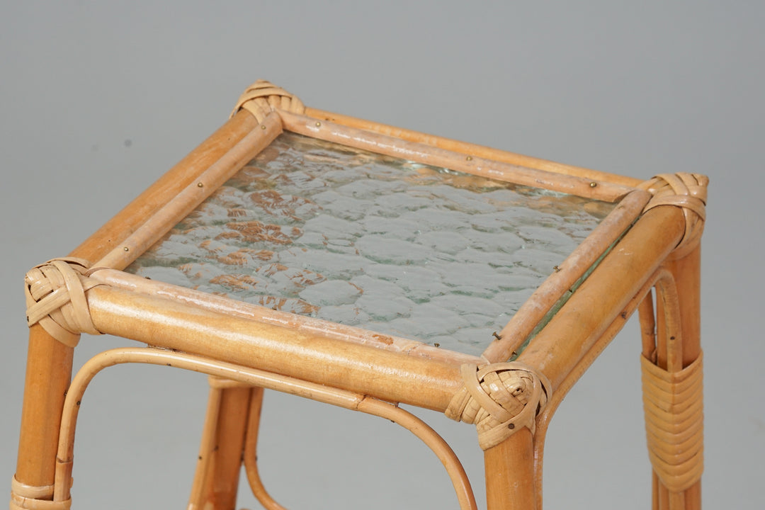 Small rattan flower table with four legs and square glass top. 