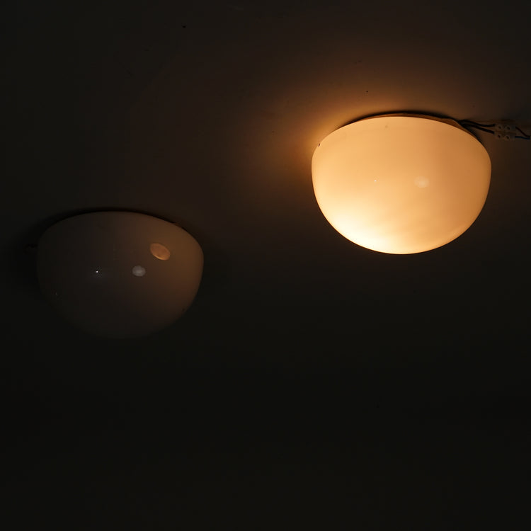 Two ceiling lamps. The glass is cloudy white and the base is metal.