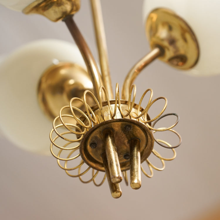 Brass frame ceiling lamp with three opal glass domes. The domes are pointing upwards. 