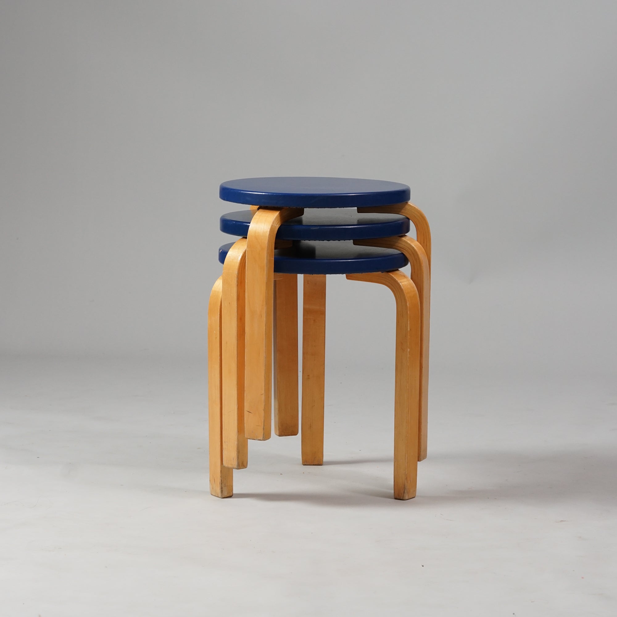 Koivusta tehty jakkara, jossa kolme jalkaa ja ympyränmuotoinen istuin. Istuimen väri on tummansininen. 