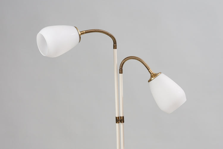 Metal lamp painted white with brass detailing. The lamp has two cloudy white glass domes. 