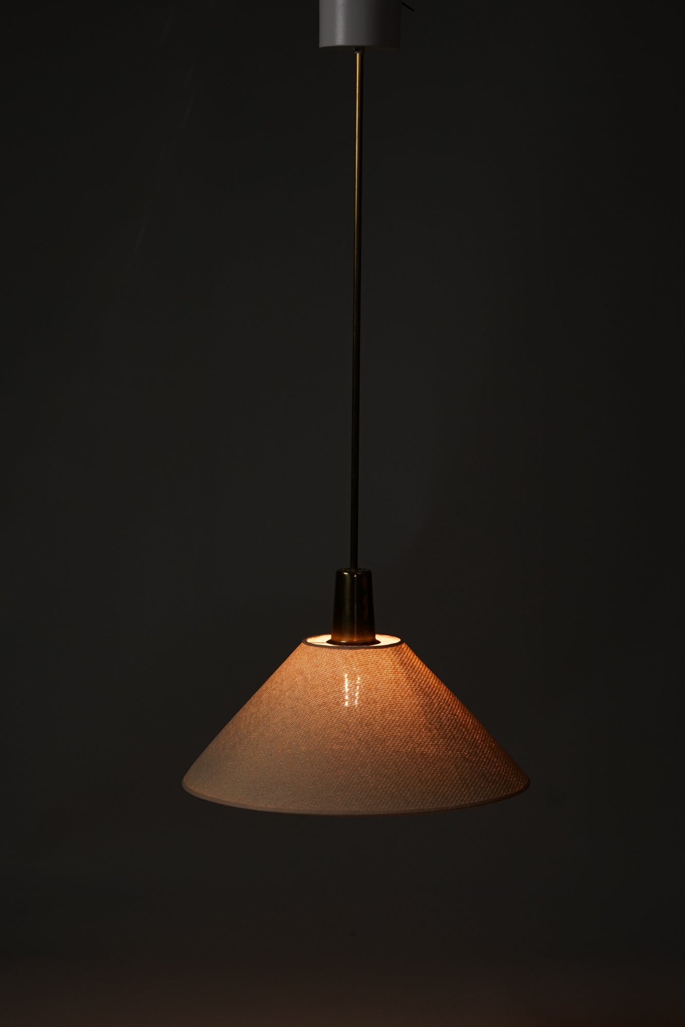 Lamp with a brass base and white fabric lamp shade.