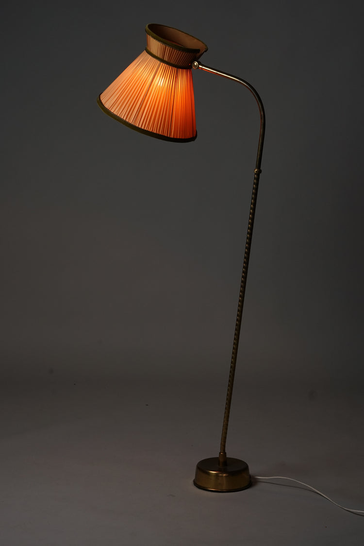 Floor lamp with brass frame. The frame is surrounded by a faux leather trim. Lampshade is burnt orange pleated fabric with forest green velvet edging.