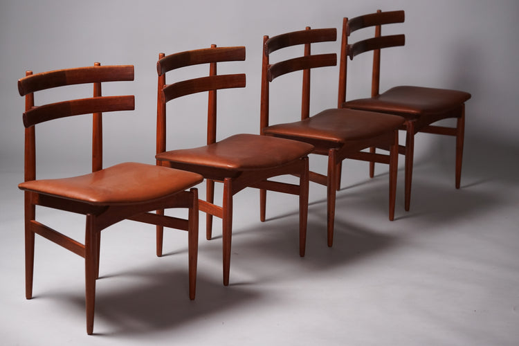 Four identical dark teak chairs with orange-brown leather seats.