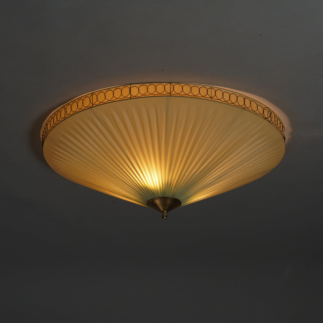 Ceiling mounted flush mount with pleated plastic shade. Round brass details around the edges and in the centre.