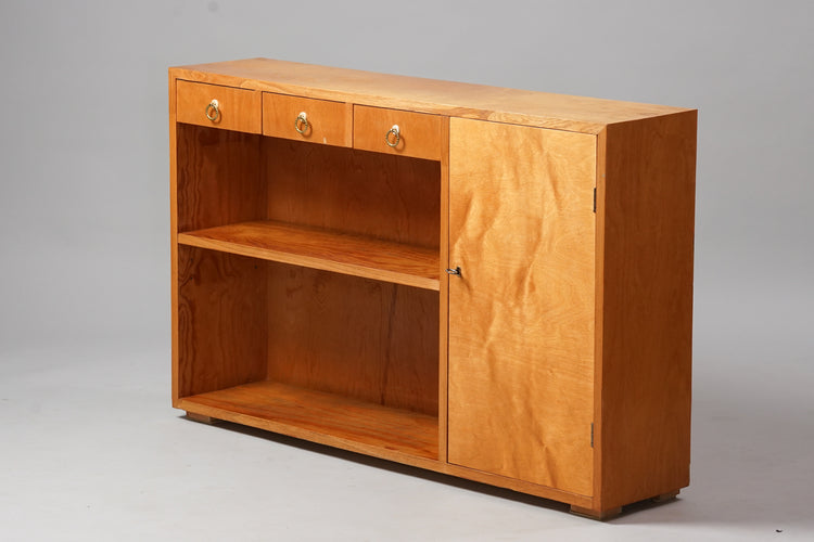 Birch bookcase with three drawers at the top with round brass handles. On the right side is a cupboard with key-lock fastening. Shelves in the middle.