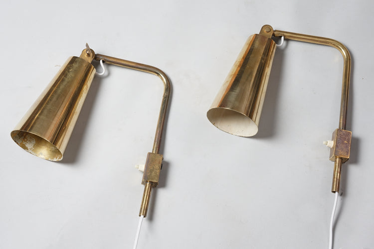 Two identical brass wall lamps. L-shaped body with cone-shaped shade at the end. At the end of the shade, a screw allows the shade to be turned. Light switch on the body.