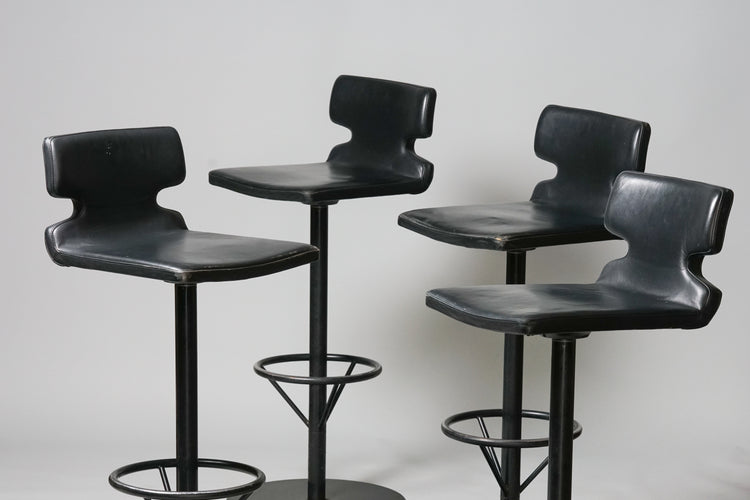 Four pieces of identical bar stools. Black leather seat. Black painted metal frame with round footrest.