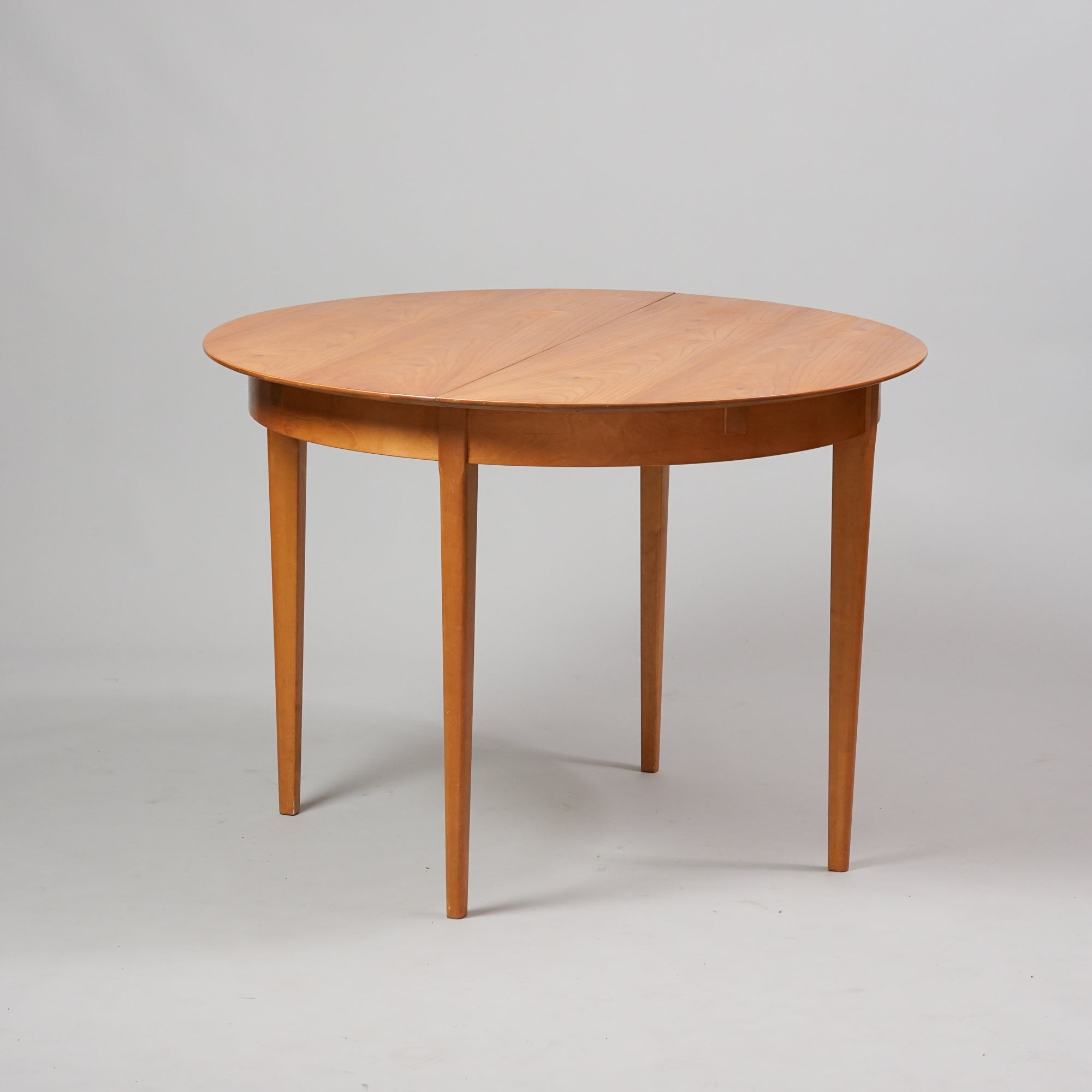 Pyöreä jatkettava pöytä, joka on tehty jalavasta ja koivusta.
