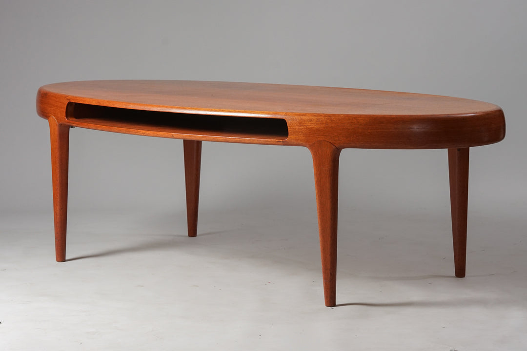 Oval coffee table. Brown teak. Four legs. Magazine stand in the middle.