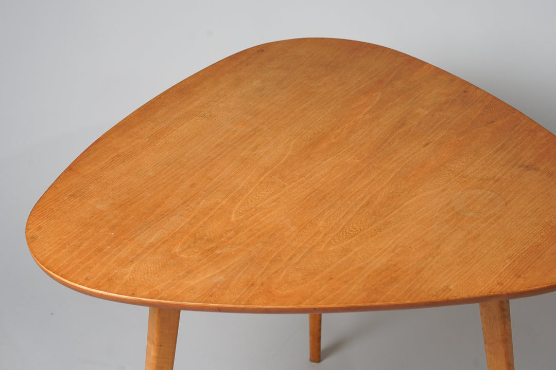 Light brown triangular coffee table. Three legs.