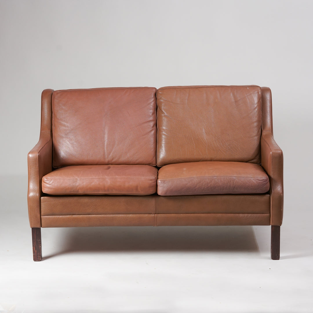 Light brown leather loveseat couch. Four teak legs. 