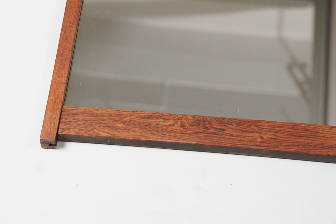 Rectangular mirror. Mirror frames in brown rosewood. The frames go lengthwise across the mirror. Manufacturer's sticker in the upper left corner.