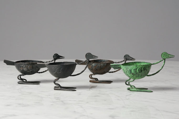 Four iron birds with their bodies working as small bowls. Three of them are black and the fourth is green.