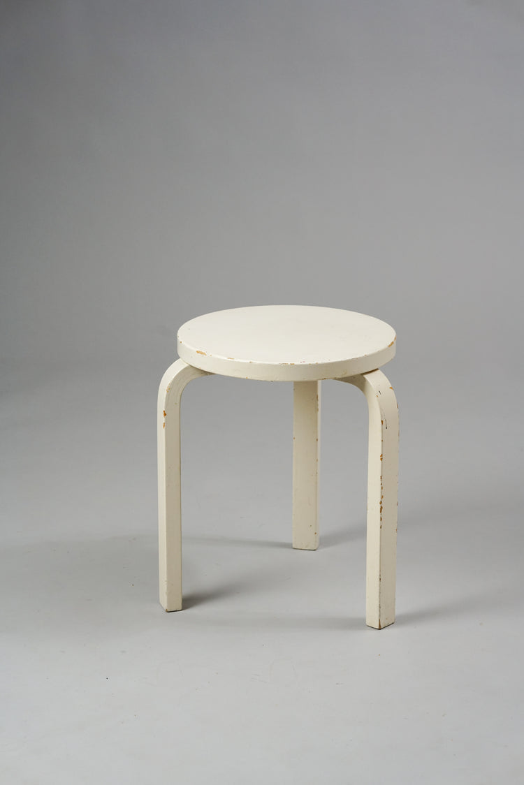 White stool with three legs and a round seat.