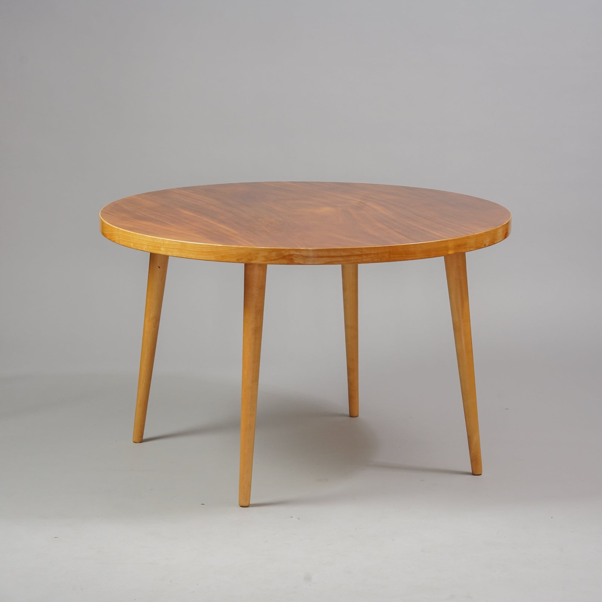 Puusta tehty pyöreä pöytä, jossa neljä jalkaa. 