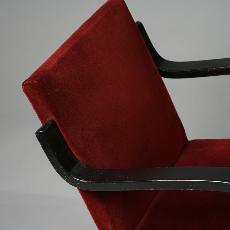 Wine red armchair with a plush fabric seat and black wooden frame.