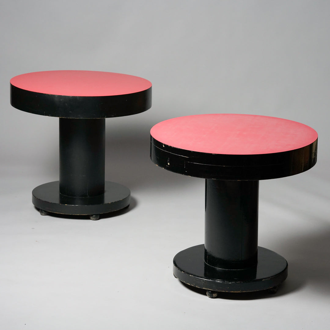 Pyöreä pöytä, jonka pöytätaso on haalean punainen. Muuten pöytä on musta ja siinä on neljä rengasta.