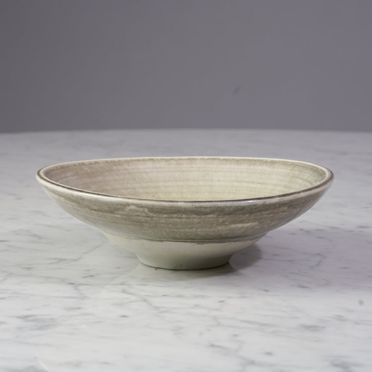 A clay bowl light brown in color. The bowl also has red and green color at the bottom.