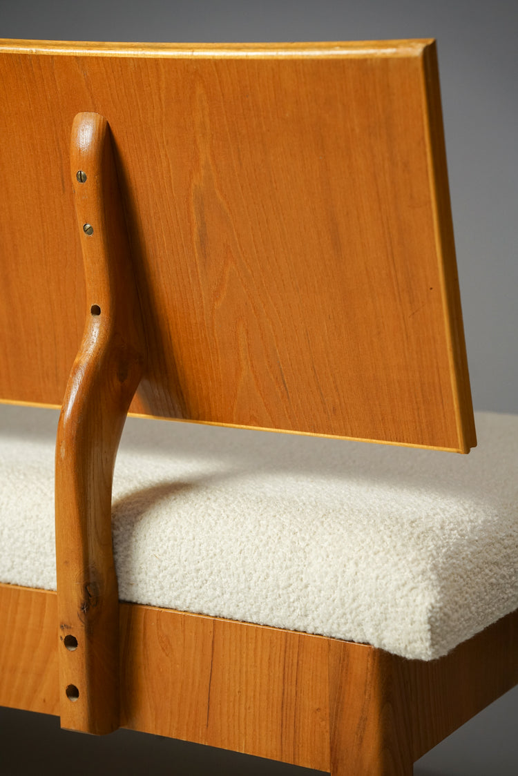 Couch made of wood. The seating is made of white fabric while the backrest is wood.